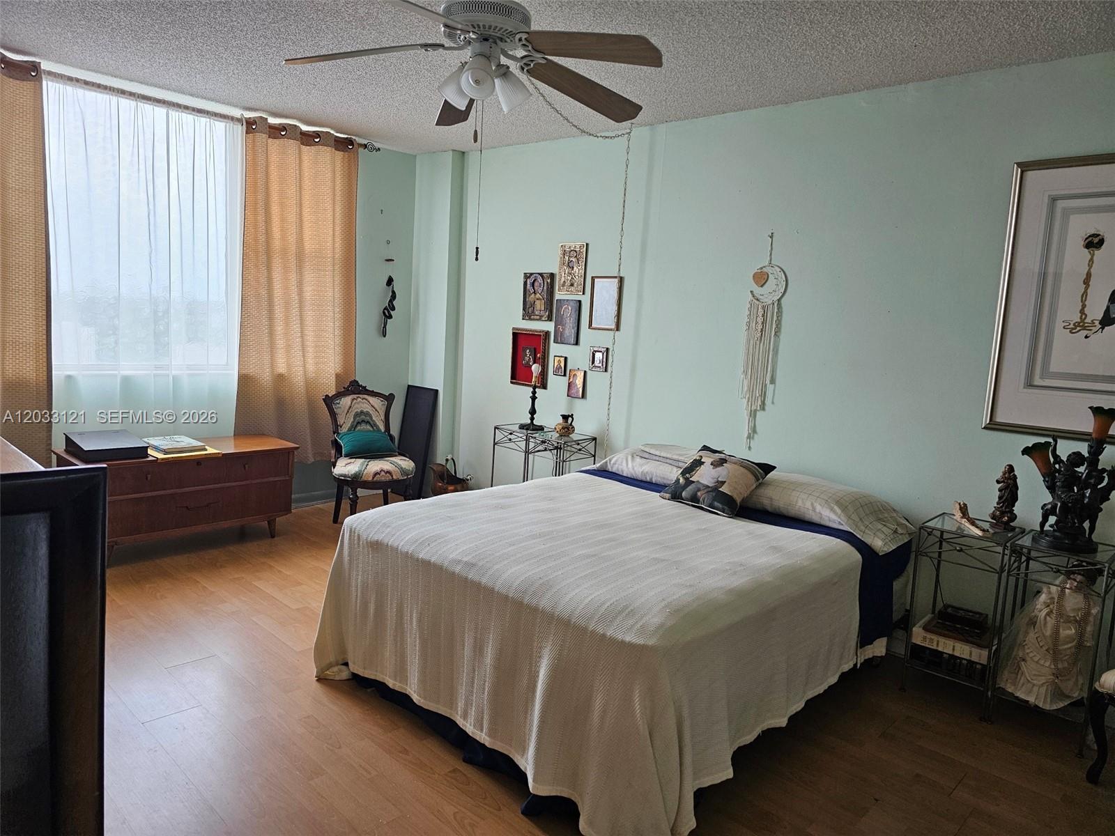A bedroom features light green walls, wood-look flooring, a ceiling fan, and a large bed — 3850 Washington St # 1011, Hollywood FL 33021, HOLLYWOOD, FL