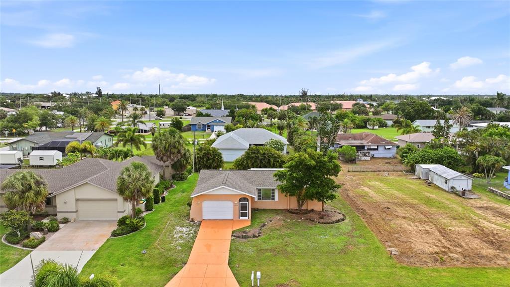 An aerial view shows a peach-colored house with a driveway next to an empty lot — 2620 WISTERIA PLACE, PUNTA GORDA, FL