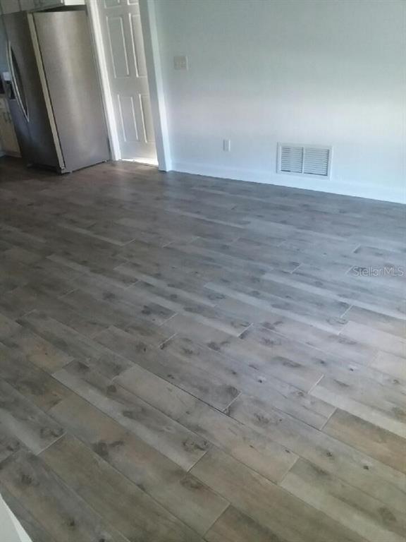 A room with light-colored wood-look flooring, a stainless steel refrigerator, and a white door — 572 PALM DRIVE, NEW SMYRNA BEACH, FL