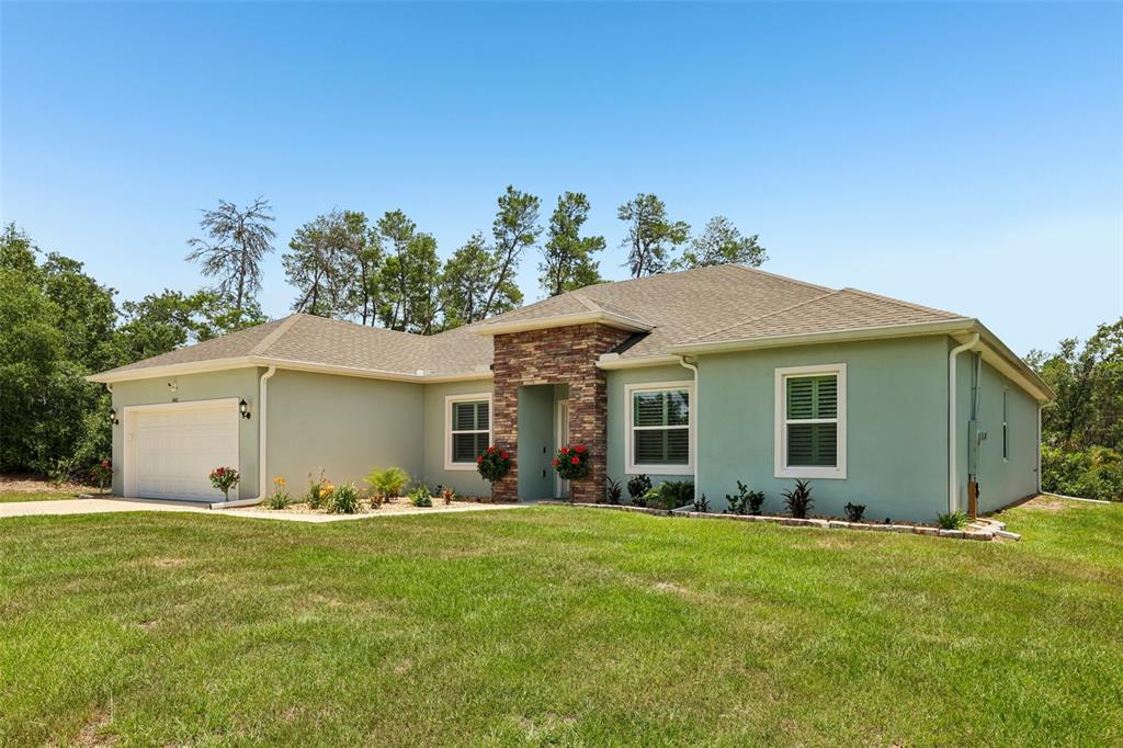 A single-story house with light green stucco, a stone-accented entryway, and a two-car garage — 4442 SW 111TH PLACE, OCALA, FL