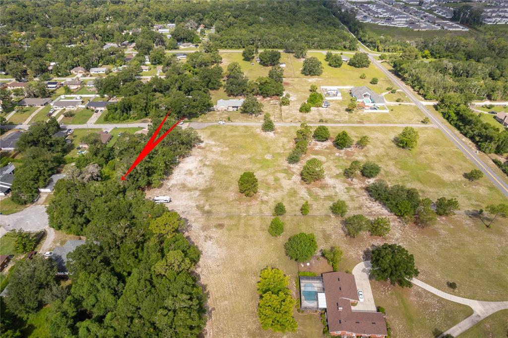 An aerial view shows a large, partially cleared grassy lot bordered by trees and houses — 1431 S MONTGOMERY STREET, DELAND, FL