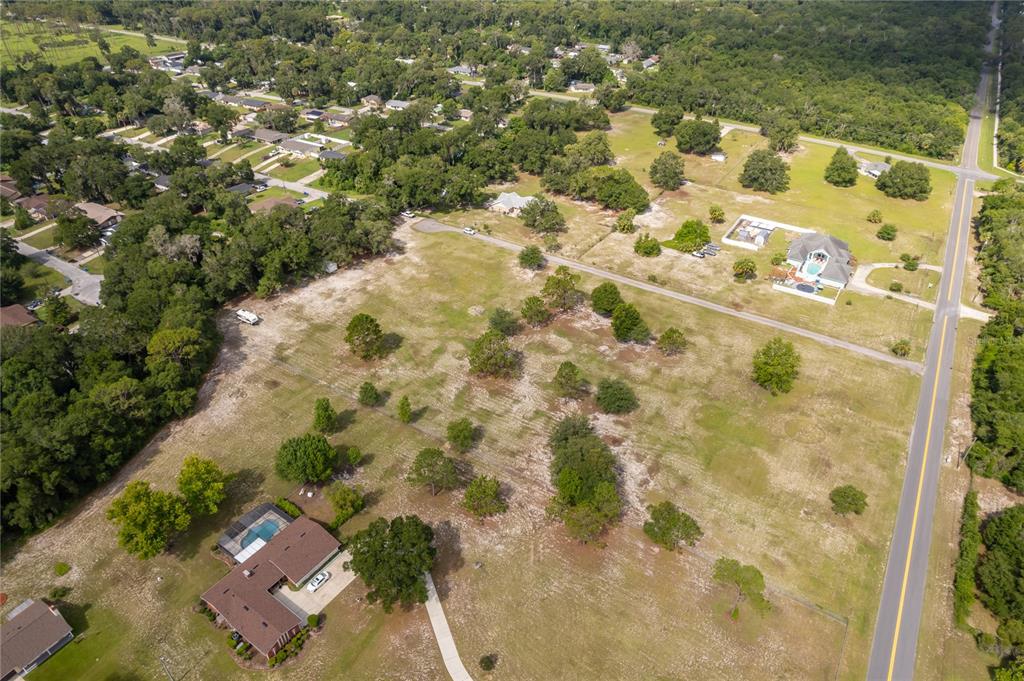 An aerial view shows a residential property with a house, pool, and surrounding grassy land — 1431 S MONTGOMERY STREET, DELAND, FL