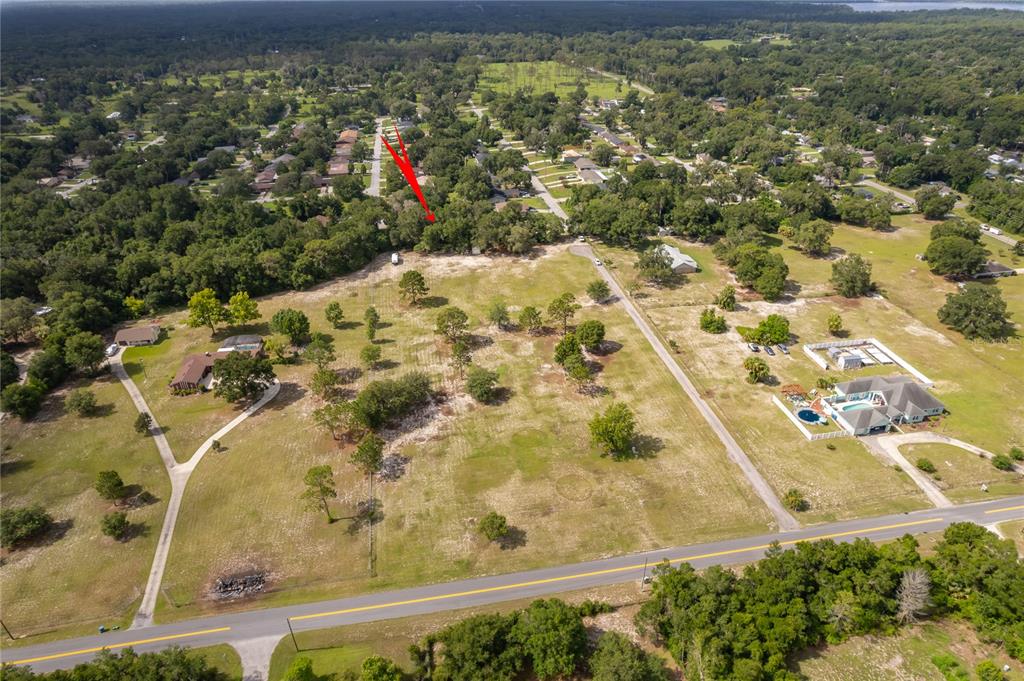 An aerial view shows a large, grassy residential lot with scattered trees and a paved road — 1431 S MONTGOMERY STREET, DELAND, FL