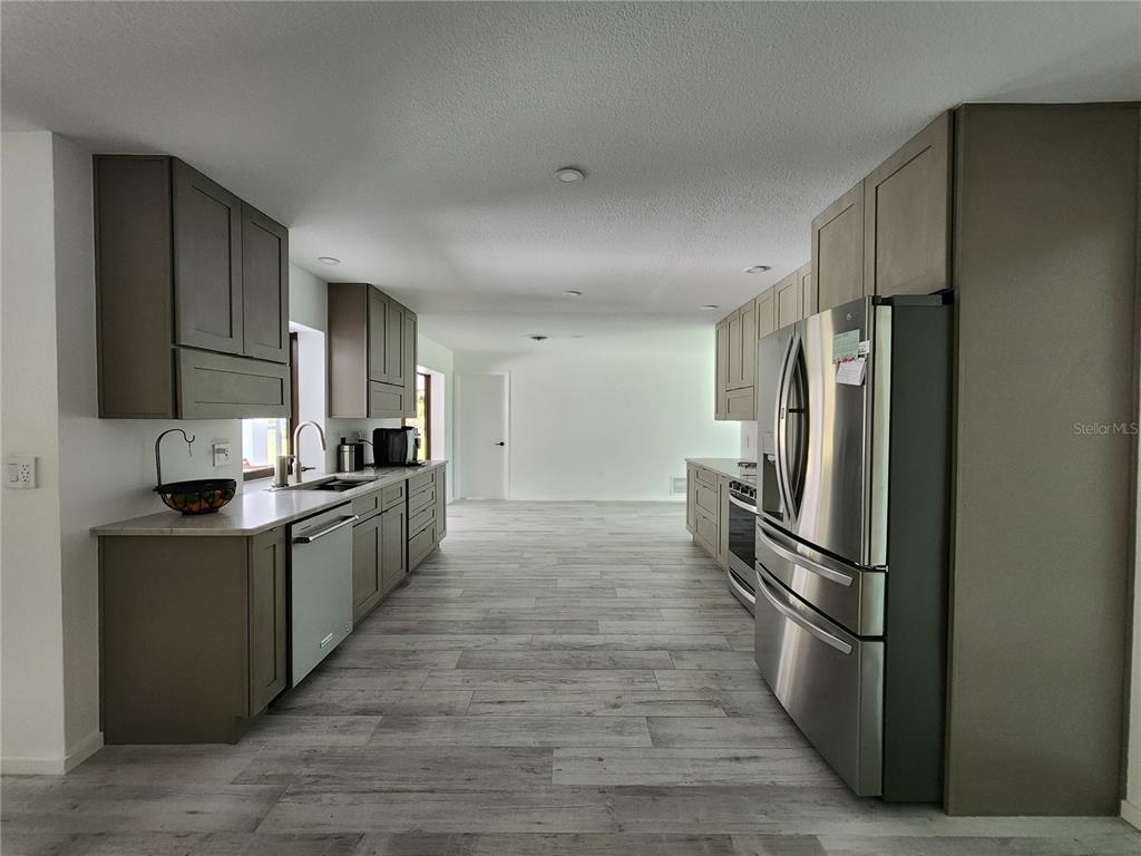 A kitchen features gray cabinets, stainless steel appliances, and light wood-look flooring — 900 CRESTWOOD ROAD, ENGLEWOOD, FL