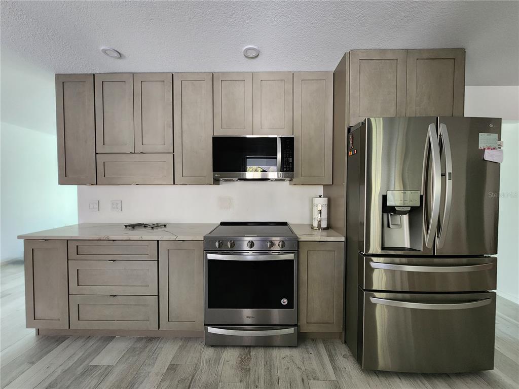 A kitchen features light wood cabinets, stainless steel appliances, and light-colored countertops — 900 CRESTWOOD ROAD, ENGLEWOOD, FL