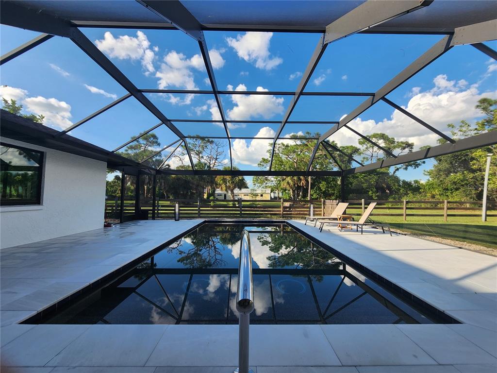 A rectangular swimming pool sits inside a screened-in lanai with light-colored tile decking — 900 CRESTWOOD ROAD, ENGLEWOOD, FL