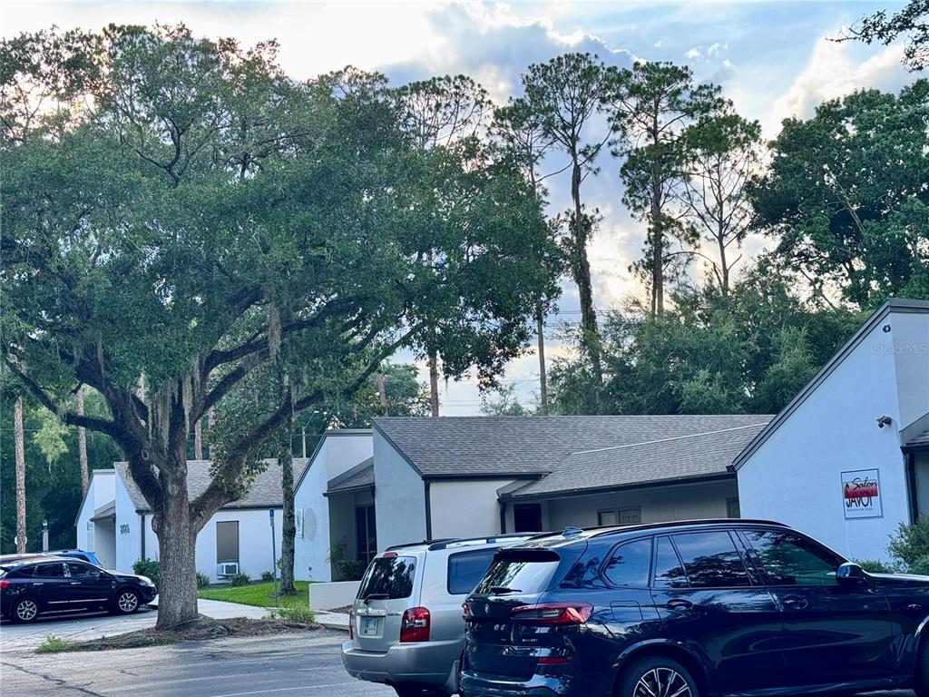 A parking lot sits in front of a single-story commercial building with trees overhead — 2727 NW 43RD STREET, GAINESVILLE, FL
