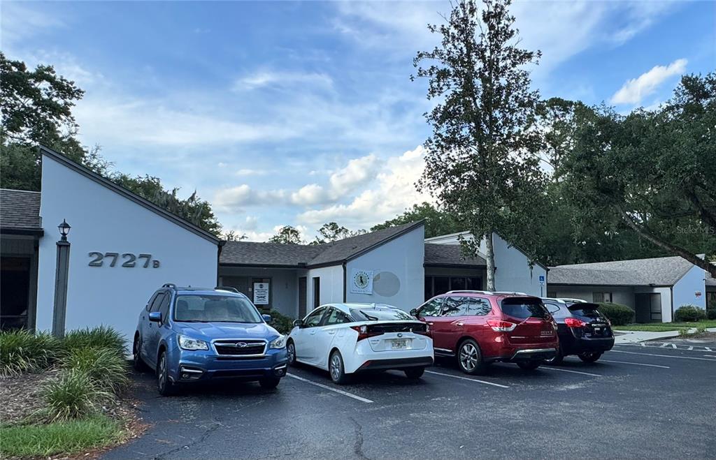 A single-story commercial building with a parking lot containing four parked cars — 2727 NW 43RD STREET, GAINESVILLE, FL