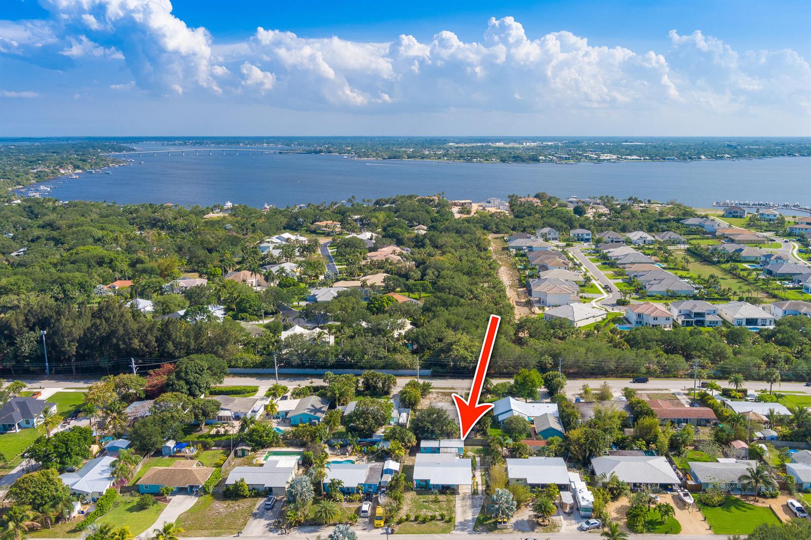 An aerial view shows a single-story house with a red arrow pointing to its roof — 2574 NE Roberta Street, Jensen Beach FL 34957, JENSEN BEACH, FL