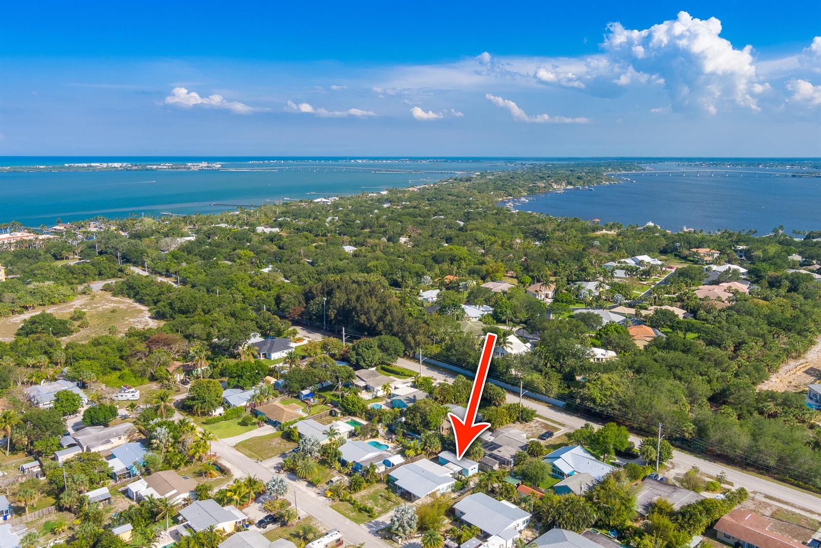 An aerial view shows a residential neighborhood with a red arrow pointing to a house — 2574 NE Roberta Street, Jensen Beach FL 34957, JENSEN BEACH, FL