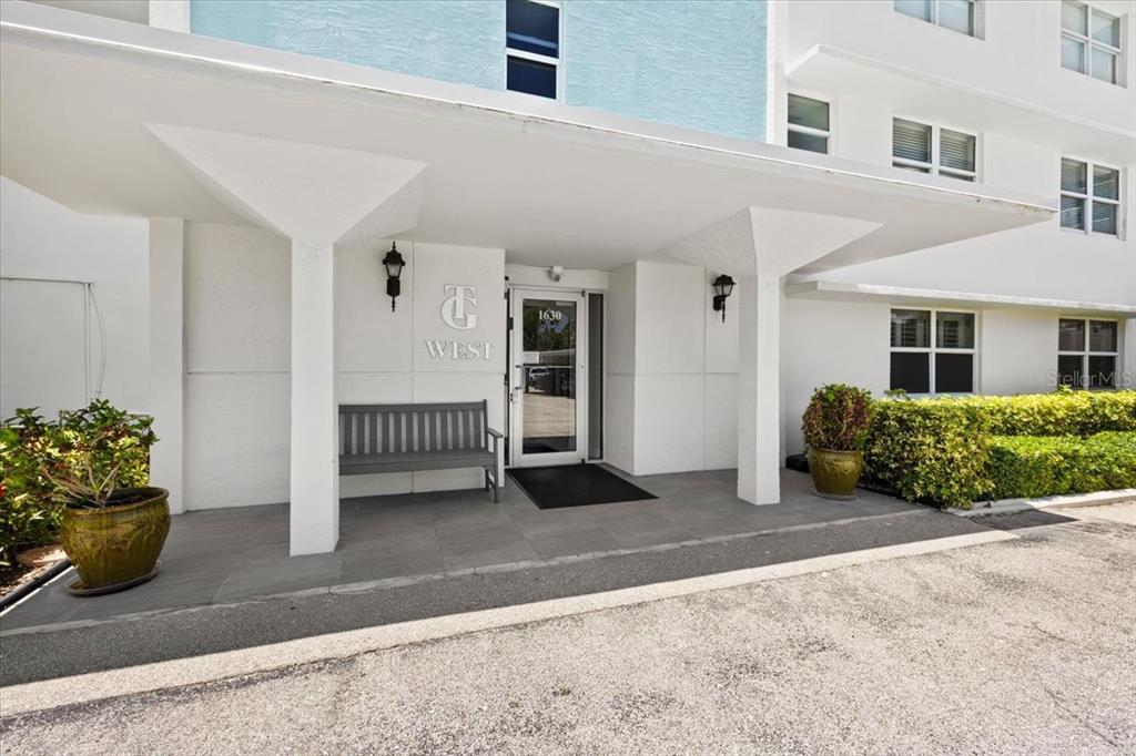 The exterior entrance of a building features a covered walkway, a bench, and potted plants — 1630 N OCEAN BLVD UNIT 1011, POMPANO BEACH, FL