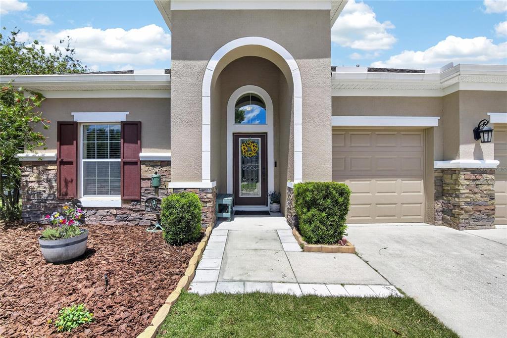 The exterior of a single-story house features a stone facade, arched entryway, and attached garage — 11321 SCRIBNER STATION LANE, LITHIA, FL