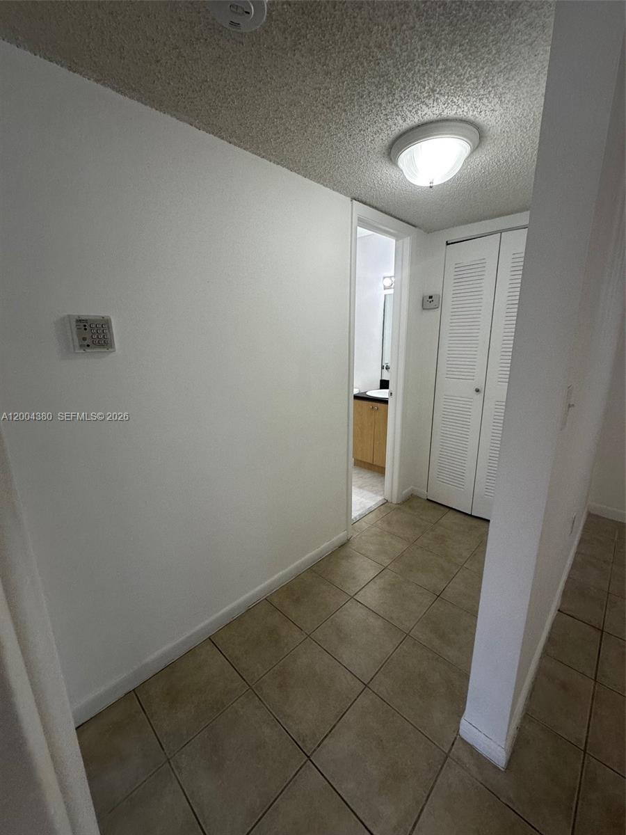 A tiled hallway leads to a bathroom and a closet with white louvered doors — 7220 NW 179th St # 201, Hialeah FL 33015, HIALEAH, FL