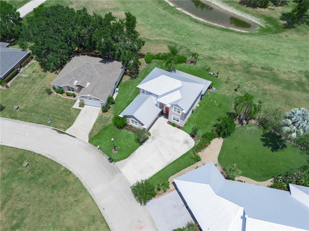 An aerial view shows three houses with metal roofs situated on a grassy suburban lot — 2910 FAIRWAY, BOWLING GREEN, FL