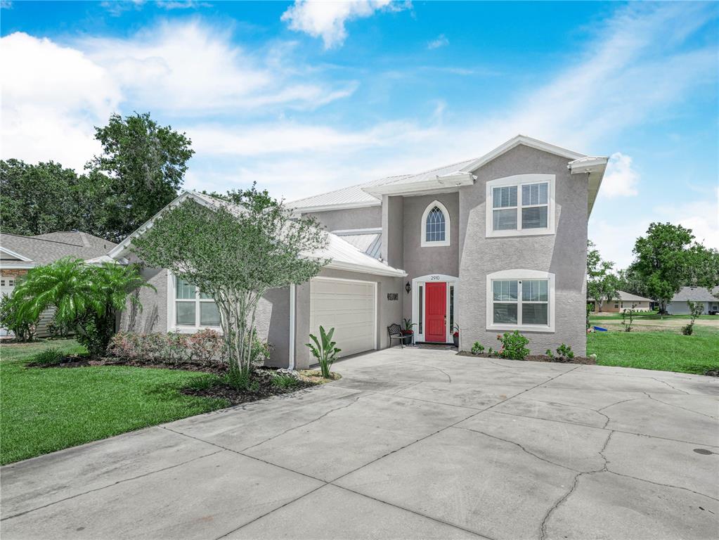 A two-story gray stucco house features a red front door and a concrete driveway — 2910 FAIRWAY, BOWLING GREEN, FL