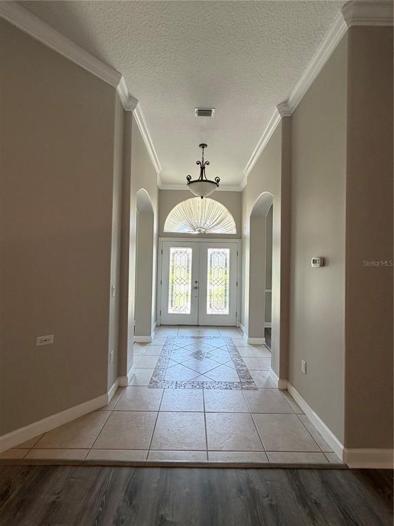 A foyer with tile flooring, a decorative inlay, a chandelier, and double glass entry doors — 1070 CEASARS COURT, MOUNT DORA, FL