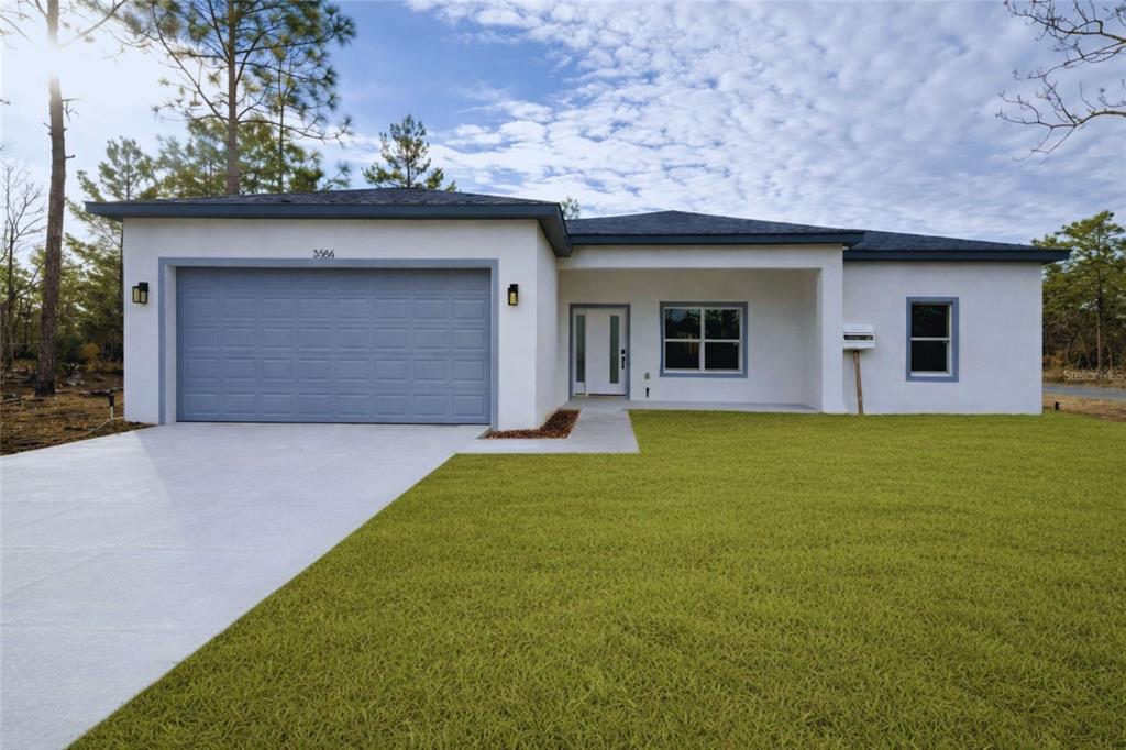 A single-story house with a white stucco exterior, gray garage door, and a grassy lawn — 3566 W HAYWARD LANE, CITRUS SPRINGS, FL