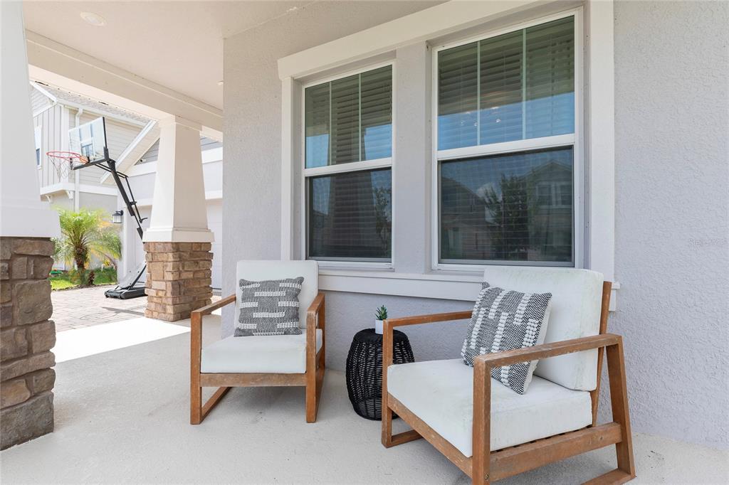 A covered porch features two wooden chairs with white cushions and a small black table — 2380 VOLUNTEER AVENUE, KISSIMMEE, FL