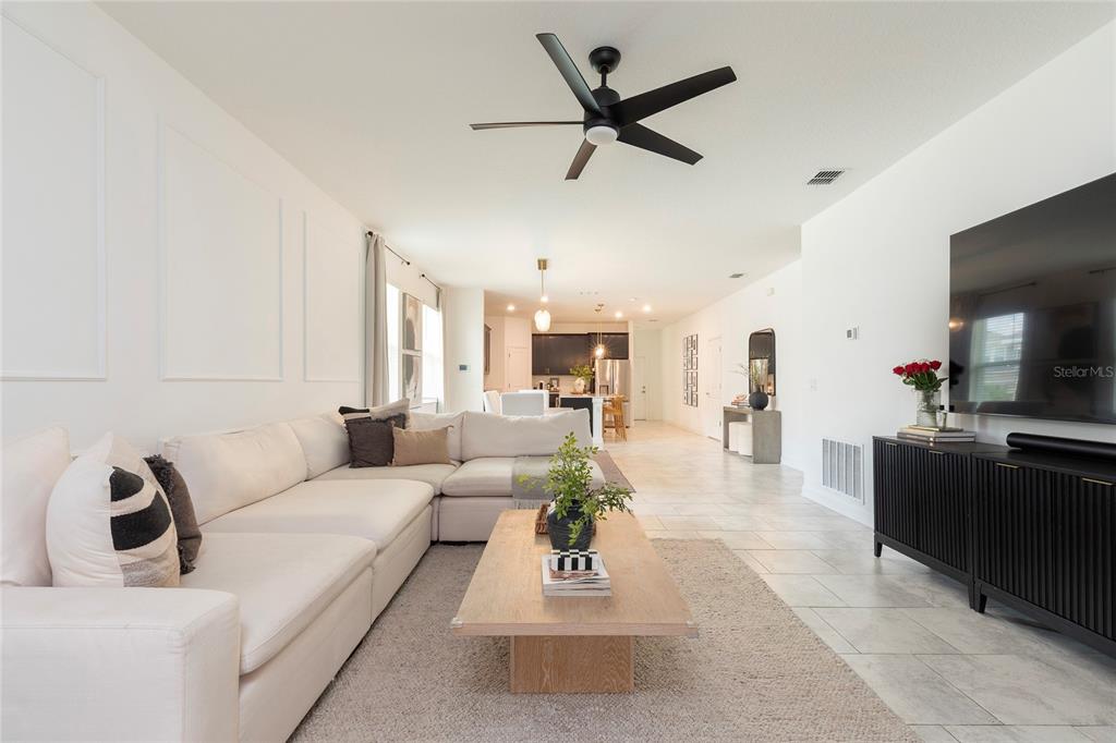A bright living room features a large white sectional, a wooden coffee table, and tile flooring — 2380 VOLUNTEER AVENUE, KISSIMMEE, FL