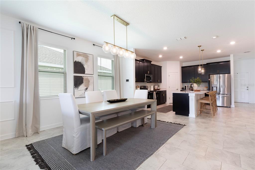 A dining area with a light wood table and white chairs sits before an open kitchen — 2380 VOLUNTEER AVENUE, KISSIMMEE, FL