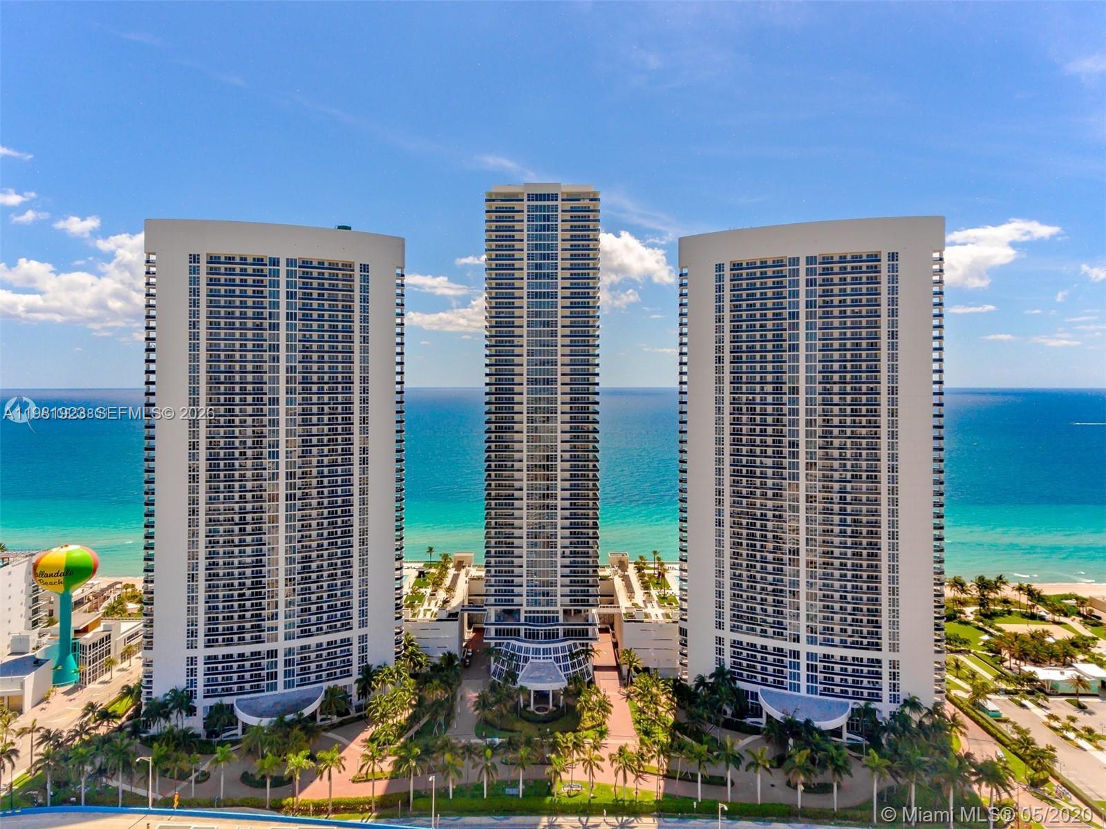 An aerial view shows three tall residential towers situated along a sandy beach — 1830 S Ocean Dr # 4004, Hallandale Beach FL 33009, HALLANDALE BEACH, FL
