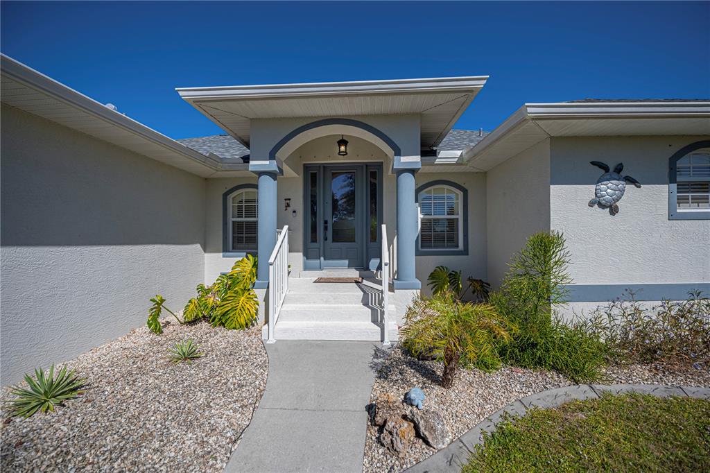 The exterior of a house features a covered entryway with blue columns and a turtle decoration — 271 ANNAPOLIS LANE, ROTONDA WEST, FL