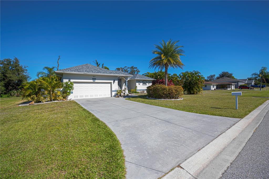 A single-story house with a white exterior, a two-car garage, and a palm tree — 271 ANNAPOLIS LANE, ROTONDA WEST, FL