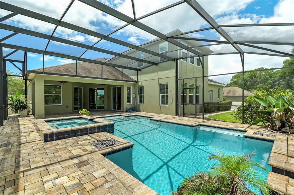 A screened-in patio features a swimming pool, a raised spa, and stone paver decking — 4473 BERRY OAK DRIVE, APOPKA, FL