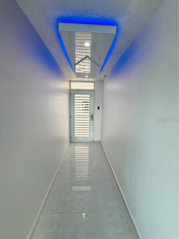 A narrow hallway features white walls, tiled floors, and a ceiling with blue accent lighting — Dos Marinas II DOS MARINAS II, NO. 110, FAJARDO, PR