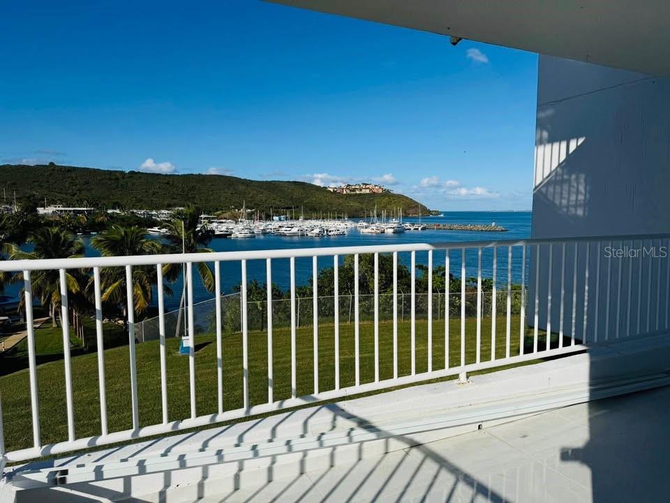 A balcony overlooks a grassy lawn, a marina with many boats, and a distant hillside — Dos Marinas II DOS MARINAS II, NO. 110, FAJARDO, PR