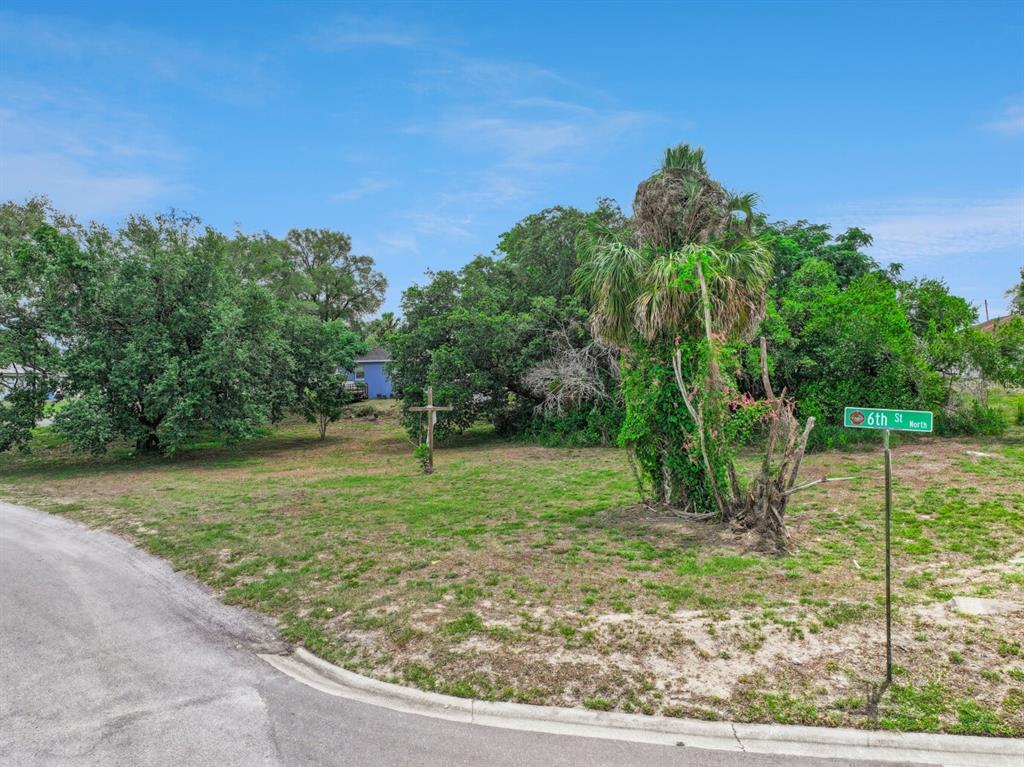 A vacant, grassy corner lot features a street sign and several mature trees — 0 LAKESHORE BOULEVARD, HAINES CITY, FL