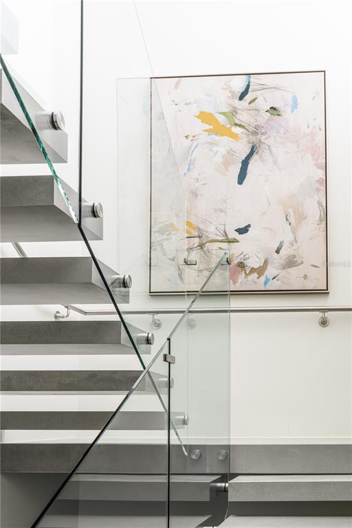 A modern staircase with concrete treads and a glass railing sits beside abstract wall art — Ocean Drive PH FOUR SEASONS PRIVATE RESIDENCES UNIT 6502, RIO GRANDE, PR