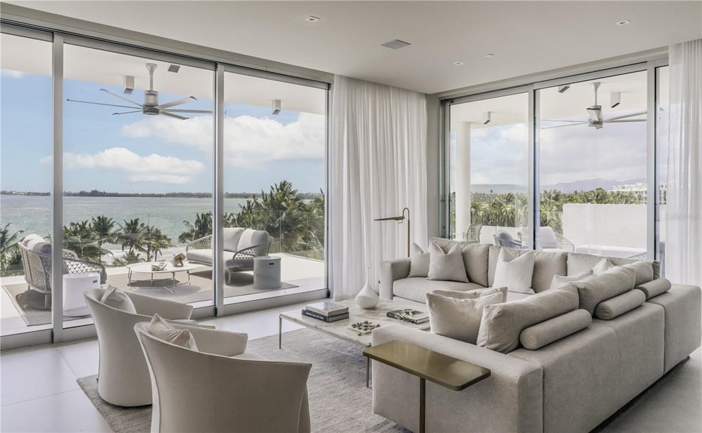 A modern living room features a large sectional sofa, floor-to-ceiling windows, and a balcony view — Ocean Drive PH FOUR SEASONS PRIVATE RESIDENCES UNIT 6502, RIO GRANDE, PR
