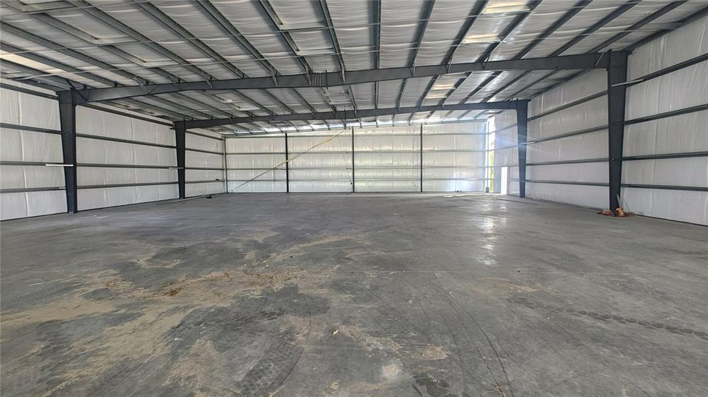 An expansive, unfinished industrial warehouse space features a concrete floor and exposed steel framing — 12142 SE COUNTY 484 HIGHWAY, BELLEVIEW, FL