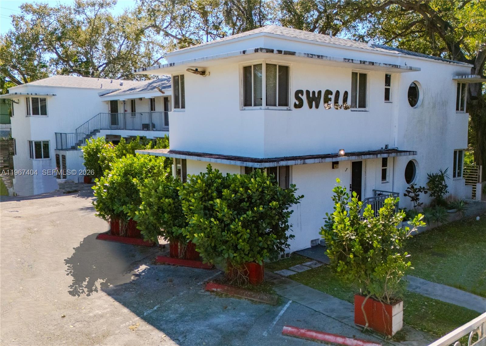An exterior view of a two-story white apartment building with a sign reading SWELL — 648 NE 80th St, Miami FL 33138, MIAMI, FL