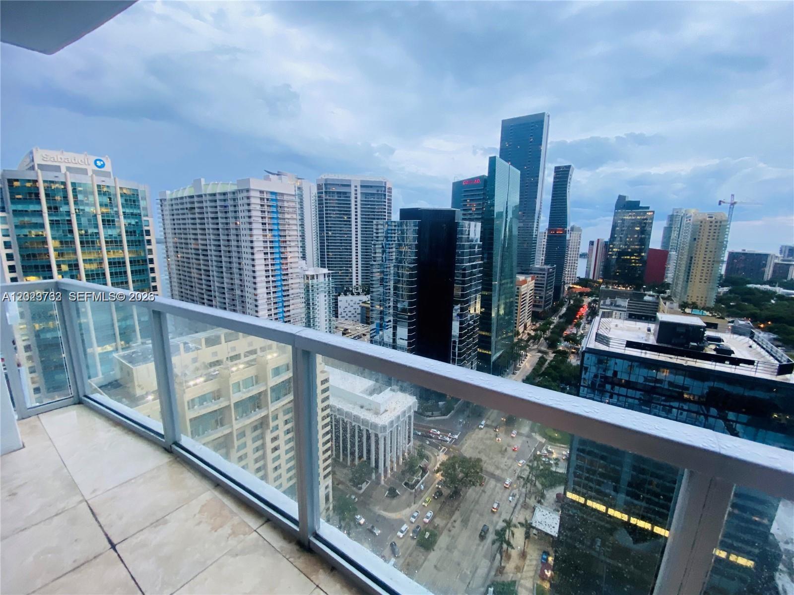 A balcony with a glass railing overlooks a dense urban skyline with multiple skyscrapers — 1060 Brickell Ave # 3109, Miami FL 33131, MIAMI, FL