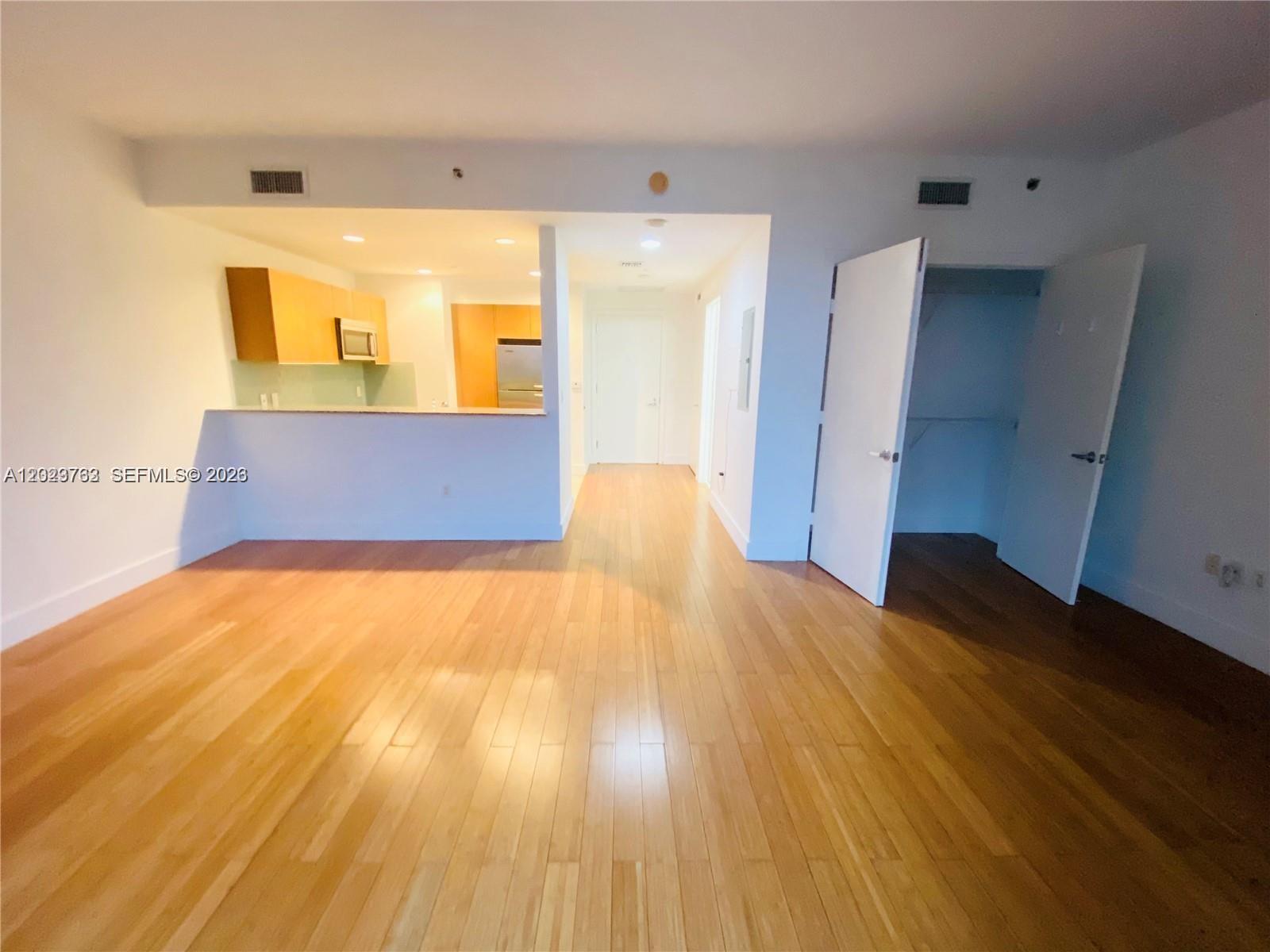 An interior view shows a living area with hardwood floors, an open kitchen, and a closet — 1060 Brickell Ave # 3109, Miami FL 33131, MIAMI, FL