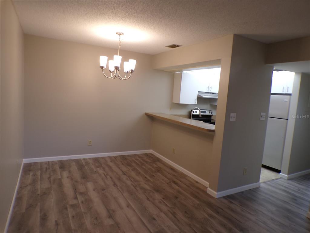 A dining area with wood-look flooring, a chandelier, and a breakfast bar overlooking the kitchen — 622 BIRD BAY DRIVE S UNIT 103, VENICE, FL