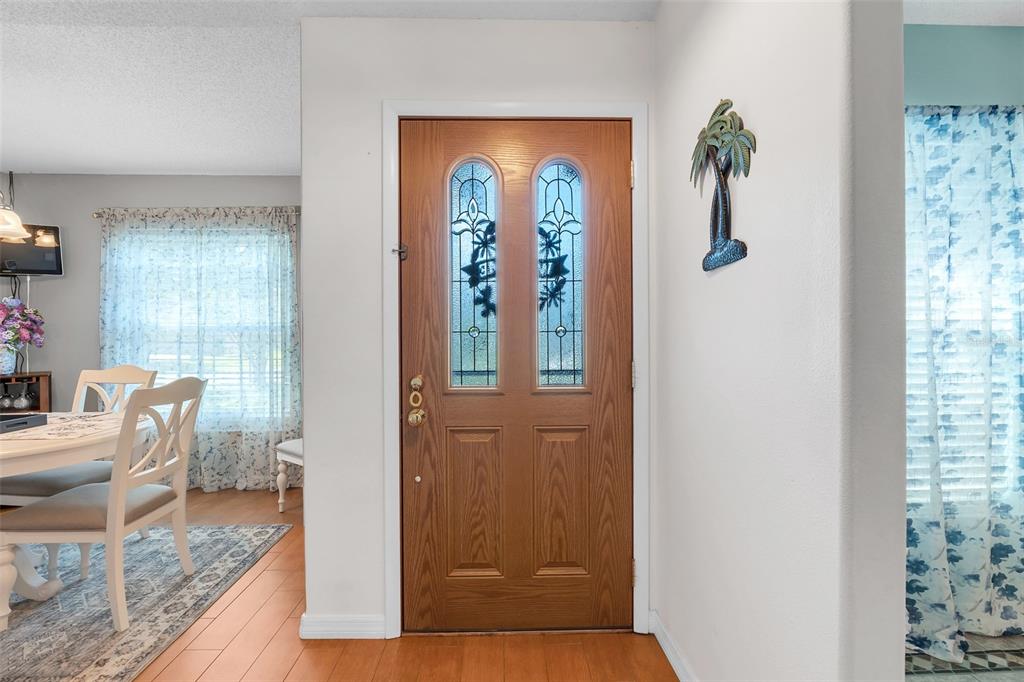 An entryway features a wood-toned front door with glass inserts and a palm tree wall decoration — 2115 KORAT LANE, MAITLAND, FL