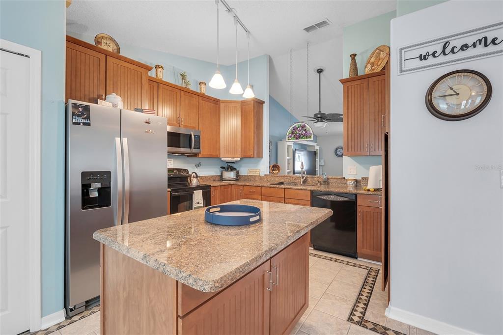 A kitchen features wood cabinets, granite countertops, a central island, and stainless steel appliances — 2115 KORAT LANE, MAITLAND, FL