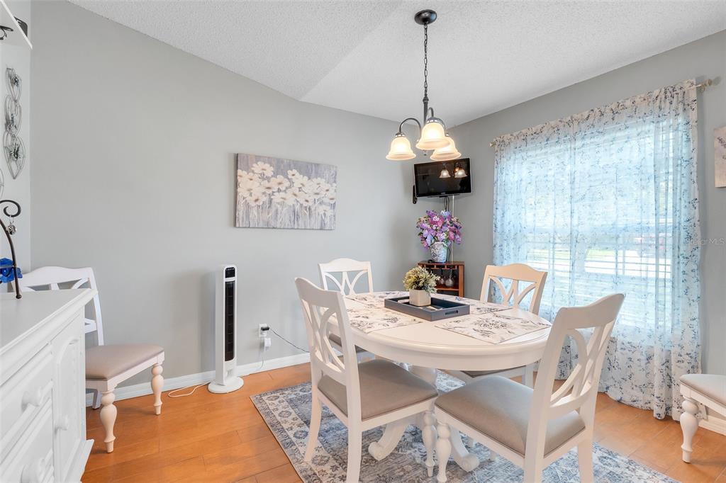 A dining room features a white table with four chairs, a chandelier, and wood flooring — 2115 KORAT LANE, MAITLAND, FL