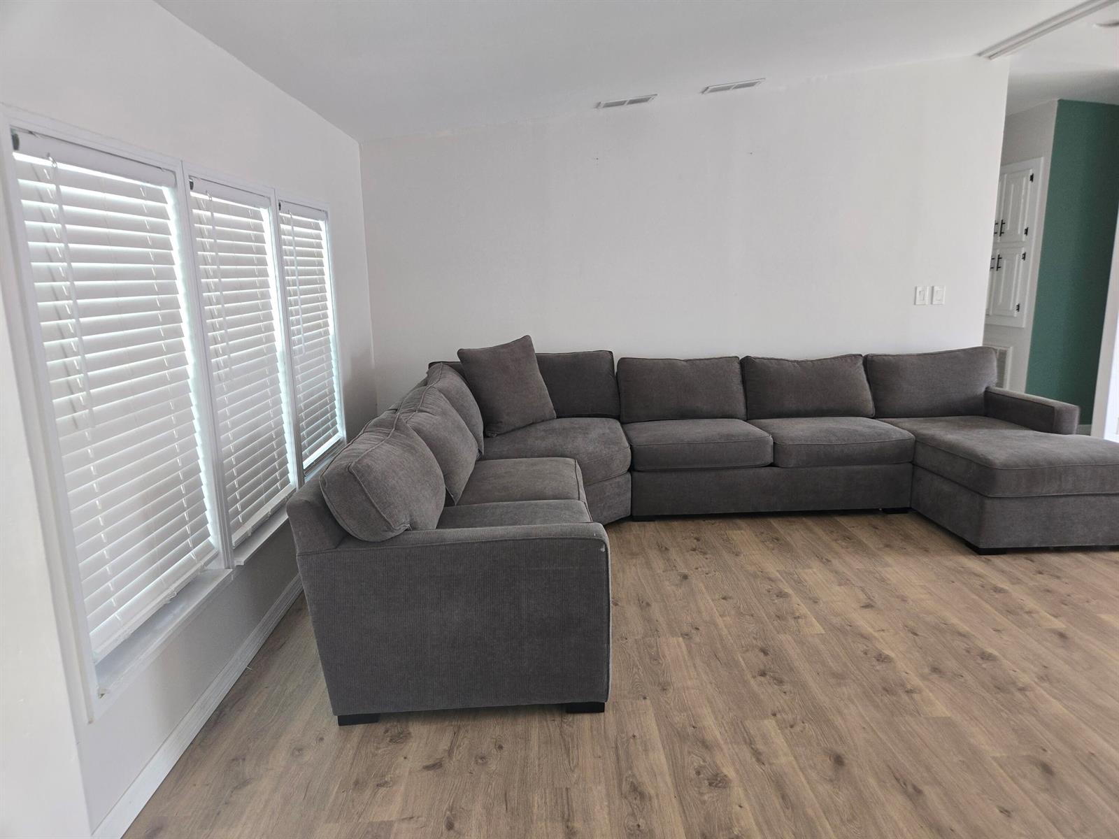 A living room features a large grey sectional sofa on light wood-look flooring — 1699 SW 35th Circle, Okeechobee FL 34974, OKEECHOBEE, FL