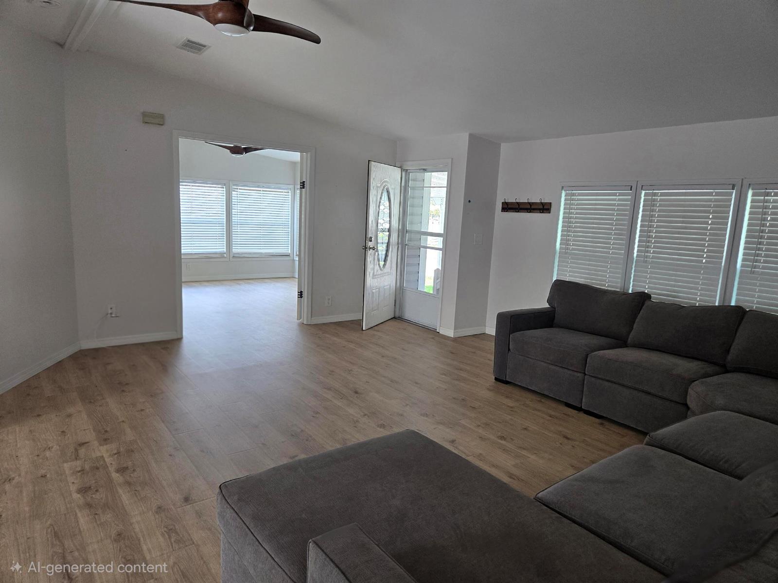 A living room features light wood-look flooring, a gray sectional sofa, and an open doorway — 1699 SW 35th Circle, Okeechobee FL 34974, OKEECHOBEE, FL