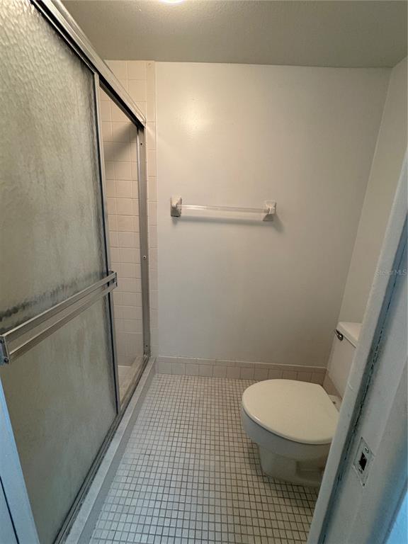 A bathroom features a glass-enclosed shower, a white toilet, and small square floor tiles — 106 LAKESIDE COURT, OLDSMAR, FL