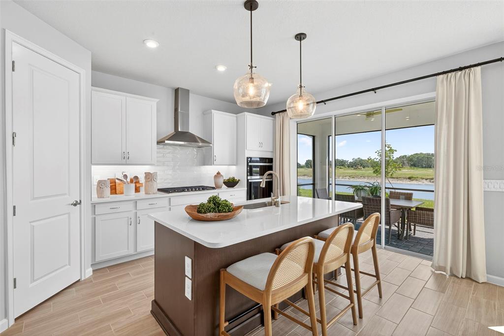 A modern kitchen features white cabinetry, a dark wood island, and sliding doors to a patio — 34877 ARBOR RETREAT DRIVE, DADE CITY, FL