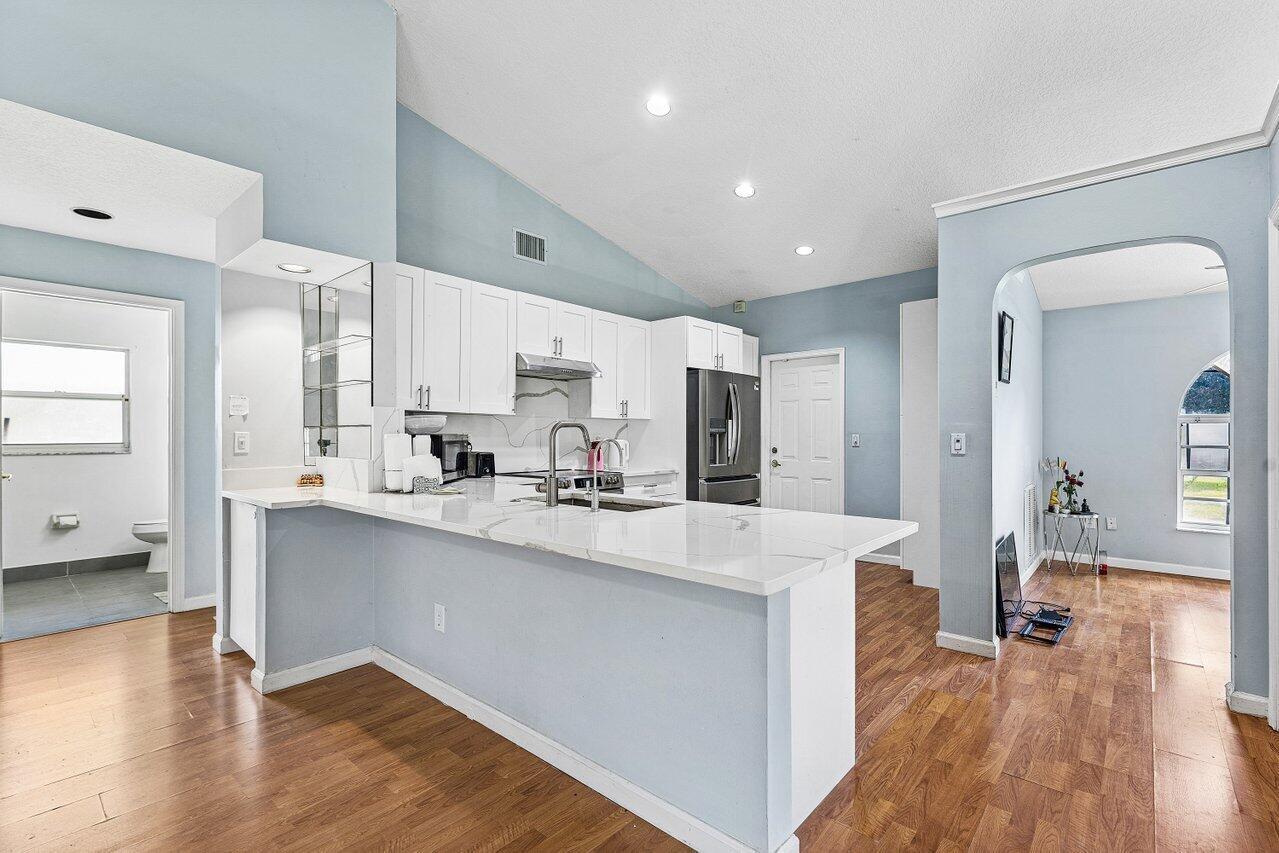 A kitchen with white cabinets, a marble-topped peninsula, and light blue walls — 13564 N 63rd Ln Lane N, FL 33412, FL