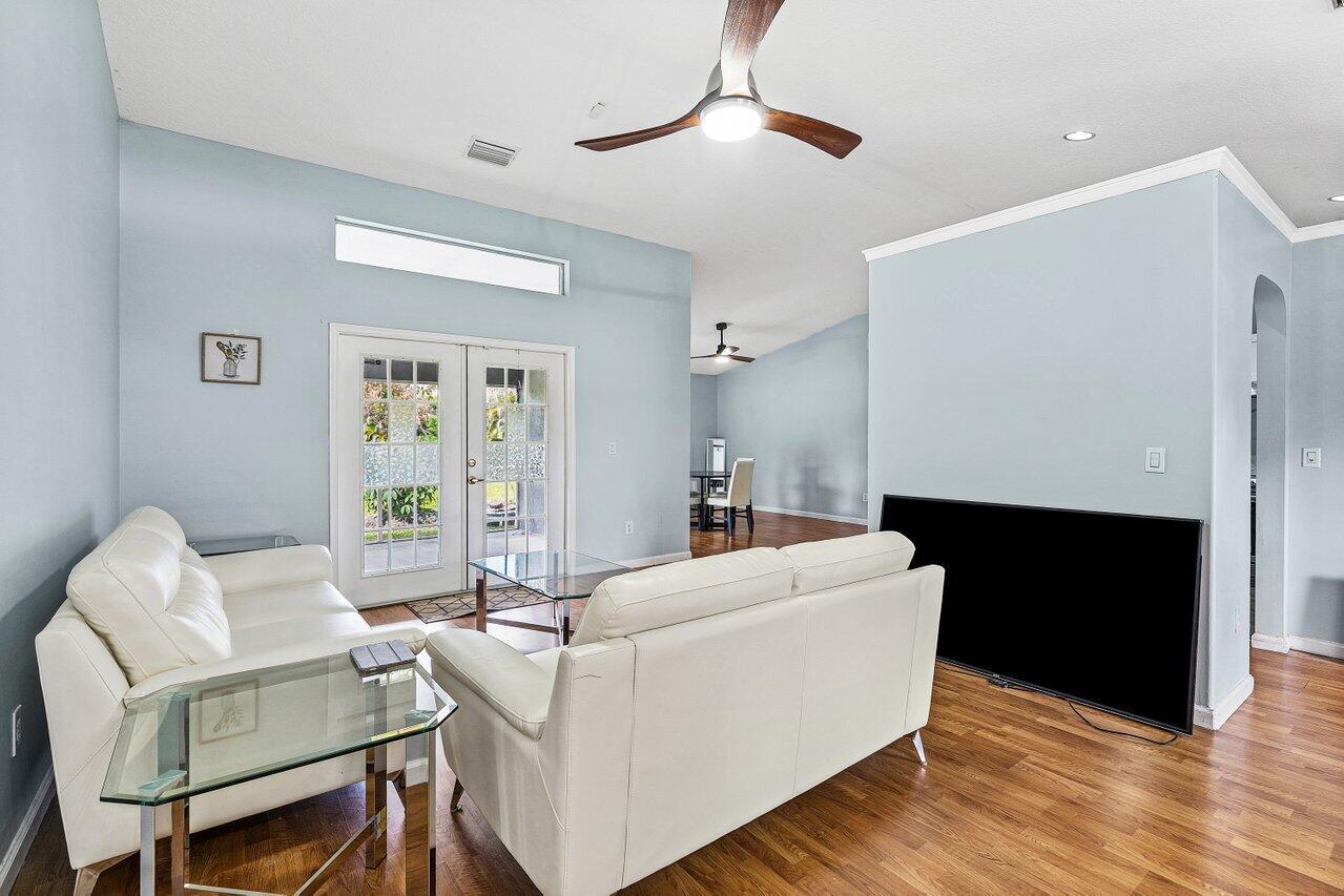 A living room features light blue walls, white leather sofas, wood flooring, and glass tables — 13564 N 63rd Ln Lane N, FL 33412, FL
