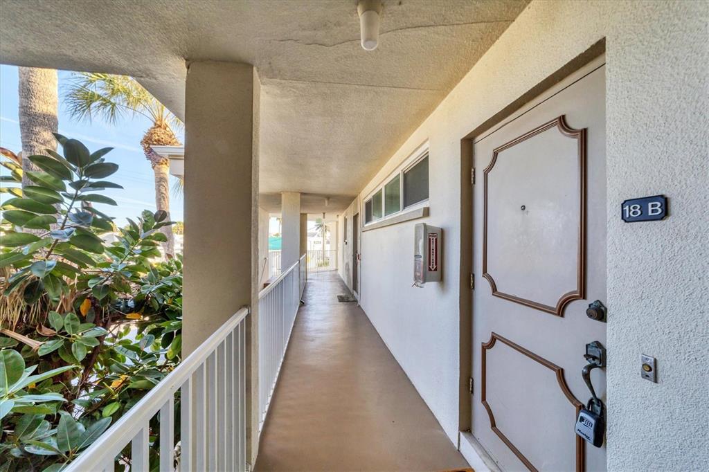 An outdoor apartment walkway features a light-colored door labeled 18 B and a white railing — 500 S WASHINGTON DRIVE UNIT 18B, SARASOTA, FL