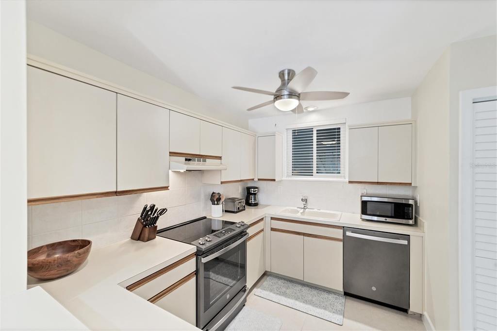 A kitchen with off-white cabinets, stainless steel appliances, and a ceiling fan — 500 S WASHINGTON DRIVE UNIT 18B, SARASOTA, FL