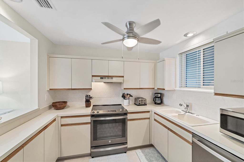A kitchen features light-colored cabinets, stainless steel appliances, a ceiling fan, and a double sink — 500 S WASHINGTON DRIVE UNIT 18B, SARASOTA, FL